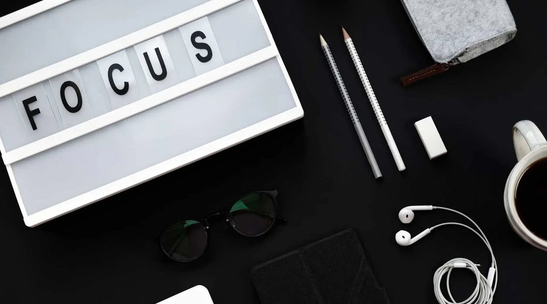 Escritorio ordenado con letrero FOCUS, lápices, taza de café y accesorios para productividad y bienestar.